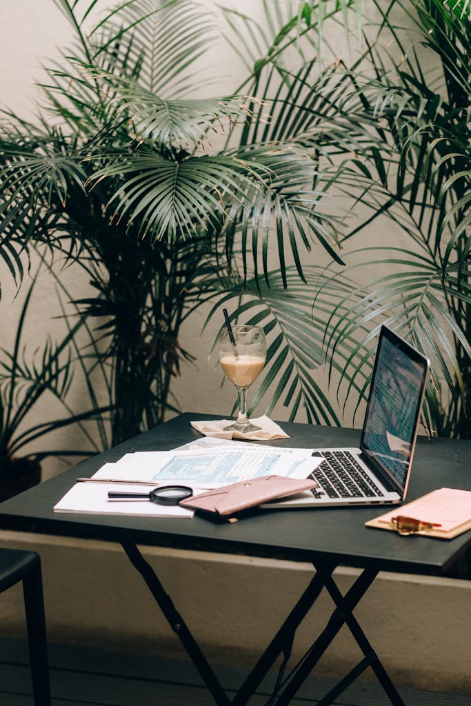 Modern workspace featuring a laptop, documents, and areca palm for a serene indoor setting.